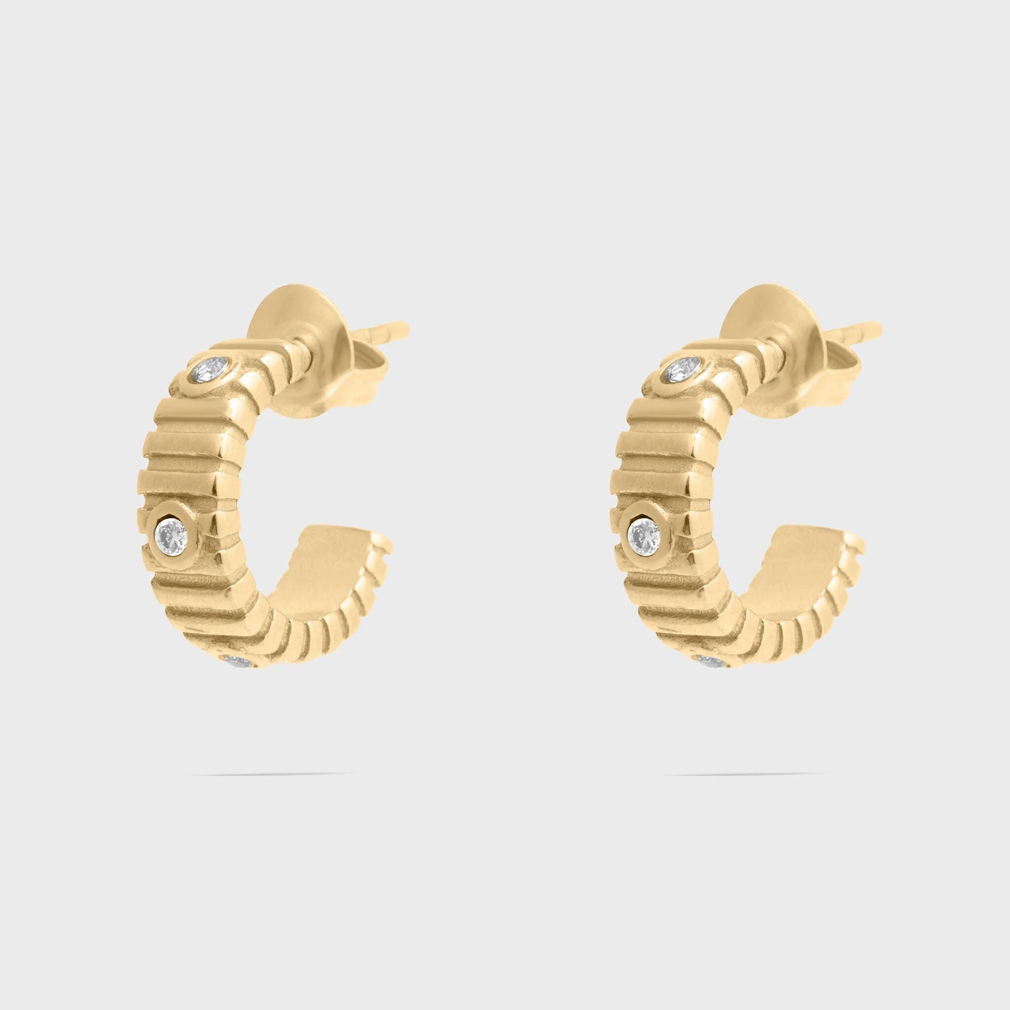 Gold hoop earrings with small diamonds on a light gray background