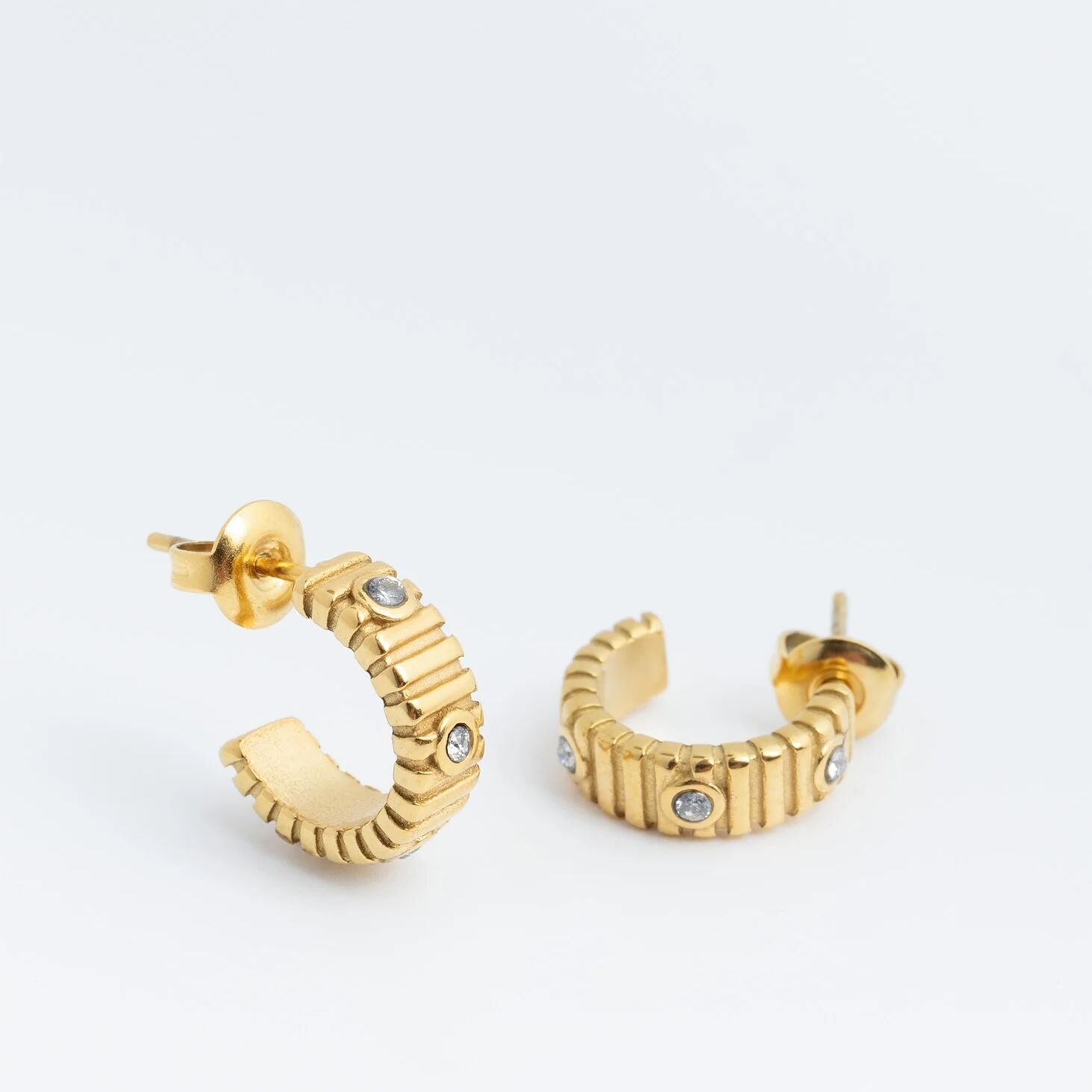 Gold hoop earrings with small stones on a white background