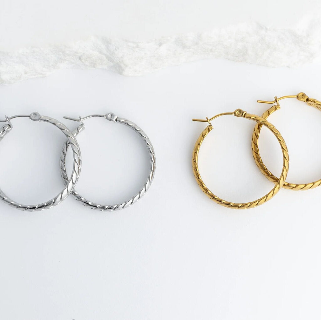 Pair of silver hoop earrings and gold hoop earrings on a white background