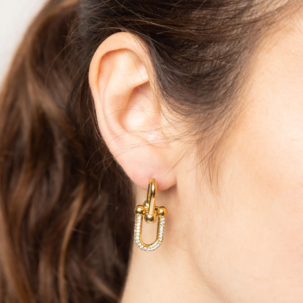 Gold hoop earring with a small diamond detail worn by a person with brown hair.