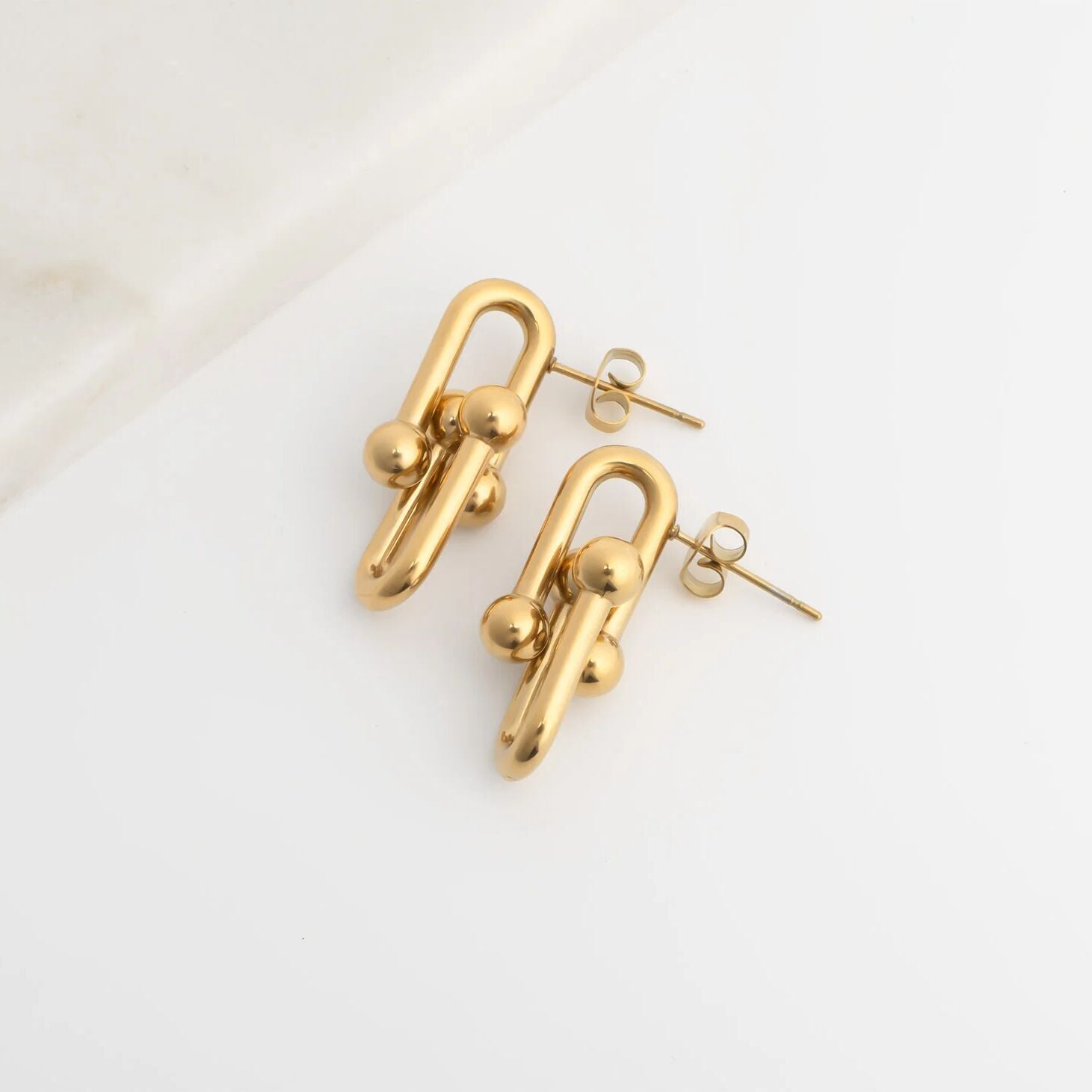 Gold chain-style earrings on a light background