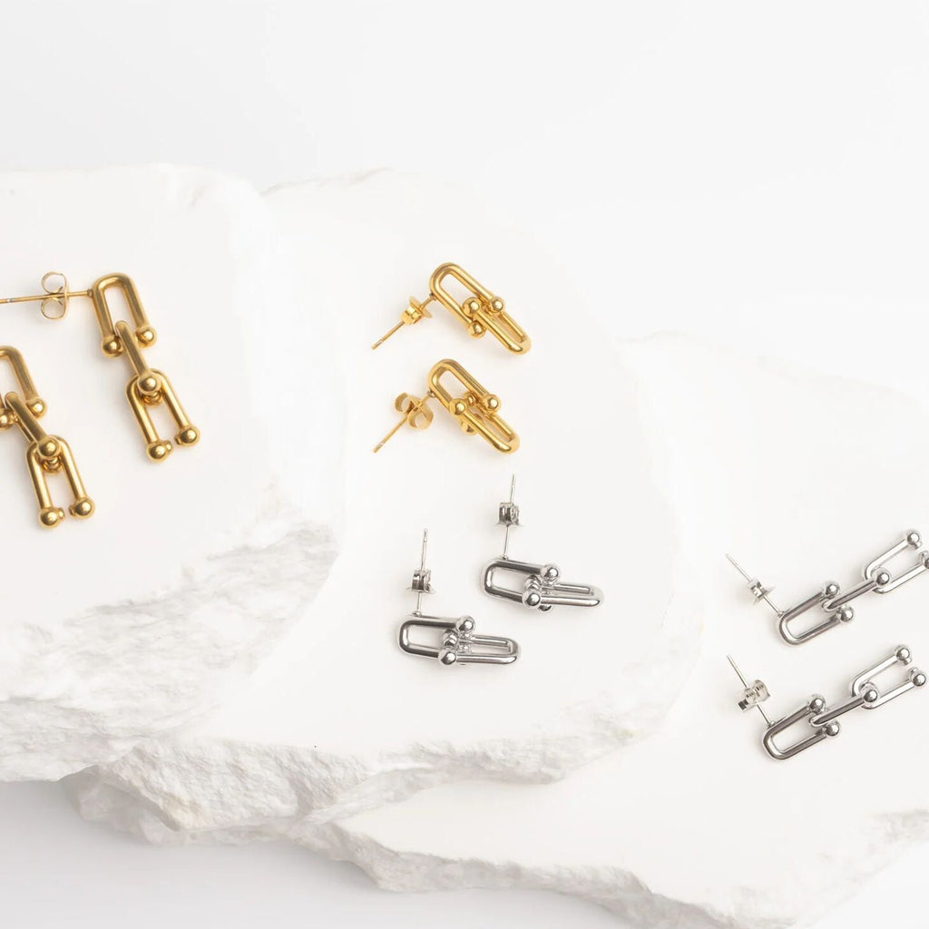 Gold and silver earrings on a white surface