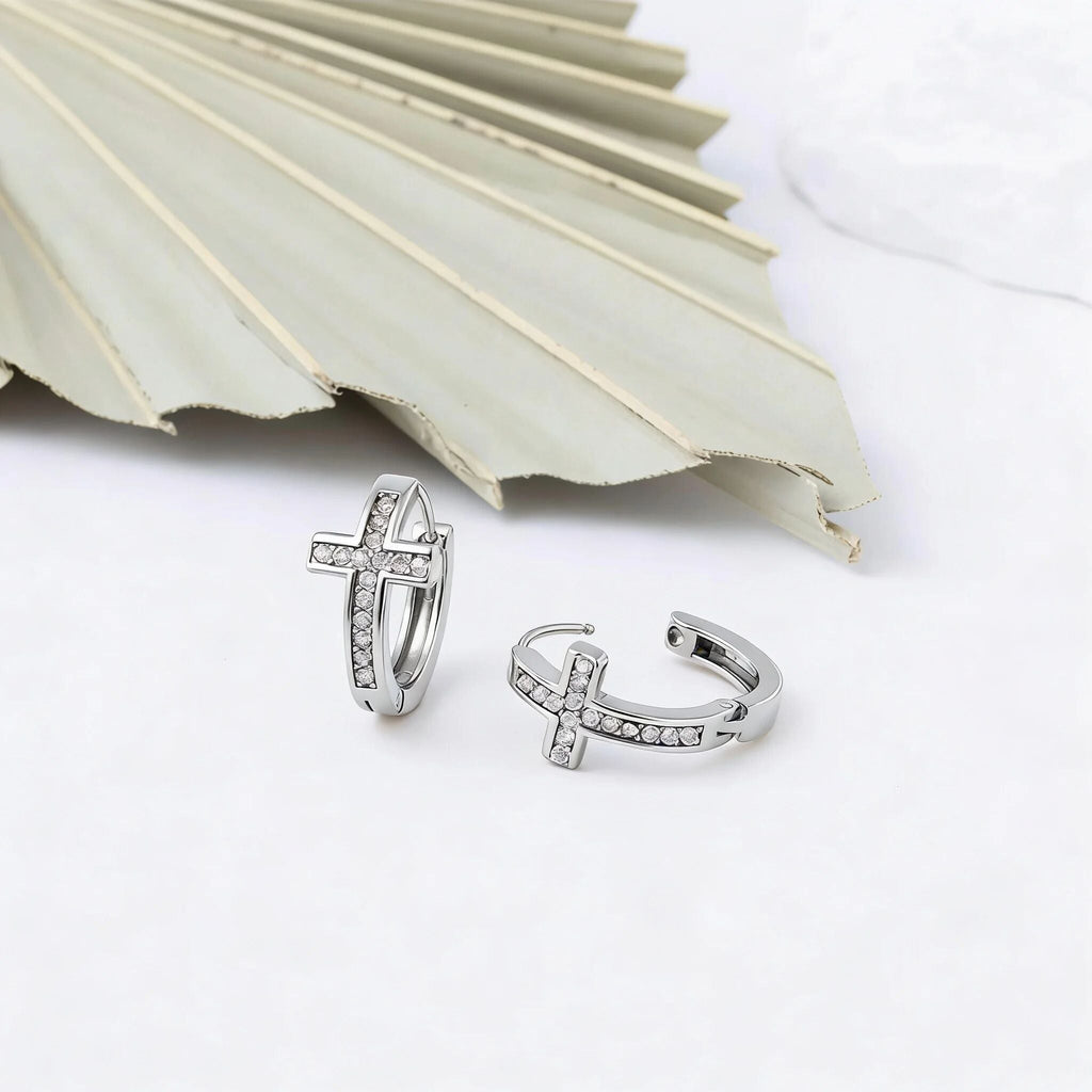 Silver cross-shaped earrings on a white surface.