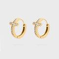 Gold cross hoop earrings with small cz stones on a light gray background