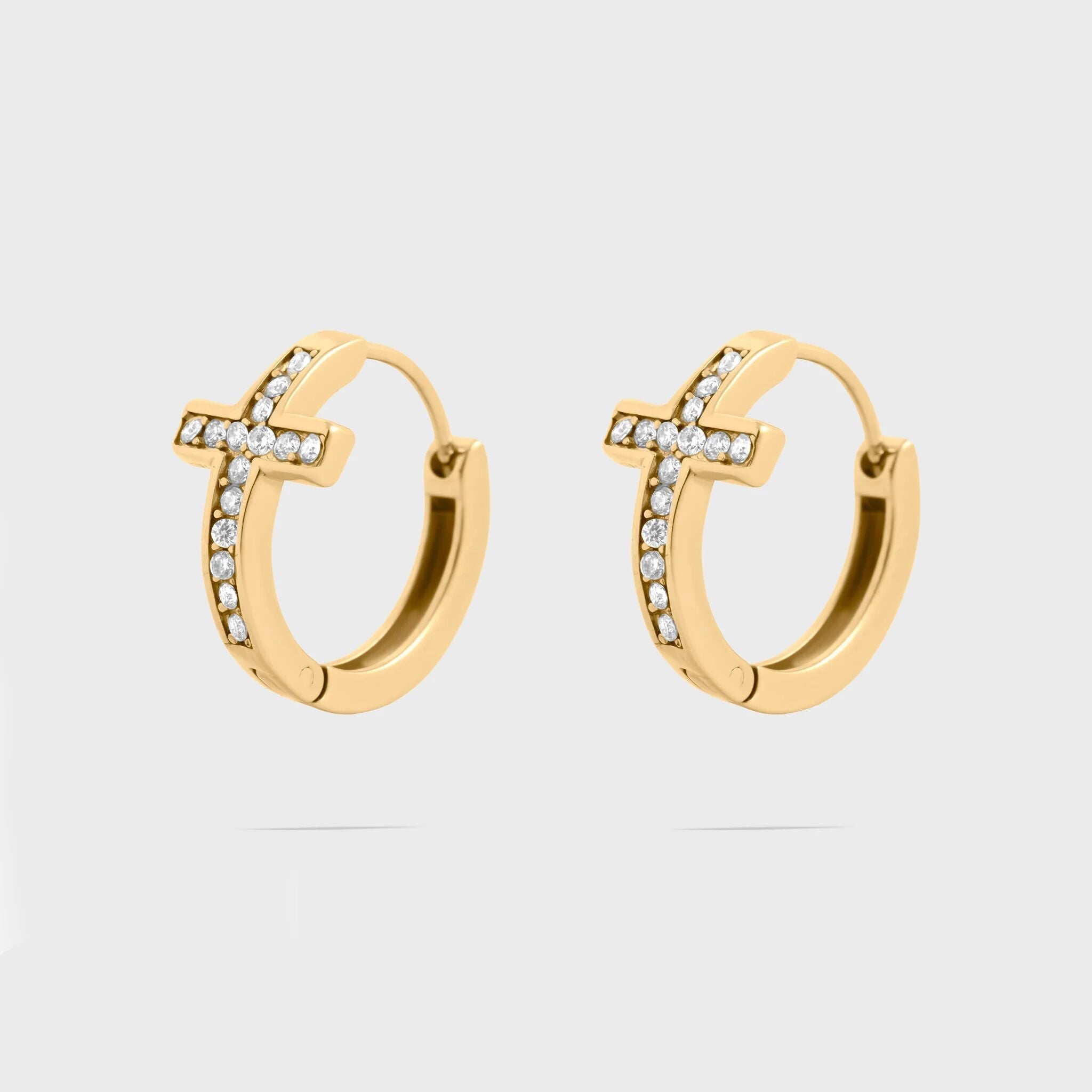 Gold cross hoop earrings with small cz stones on a light gray background