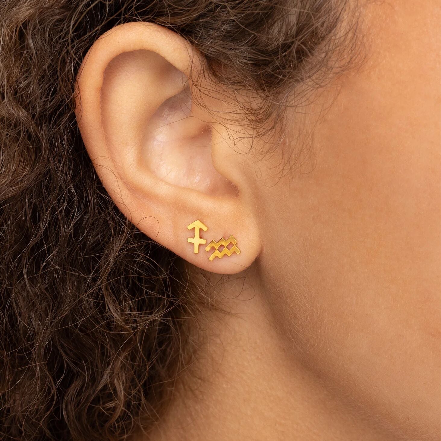 Gold earrings worn by a person with dark hair.