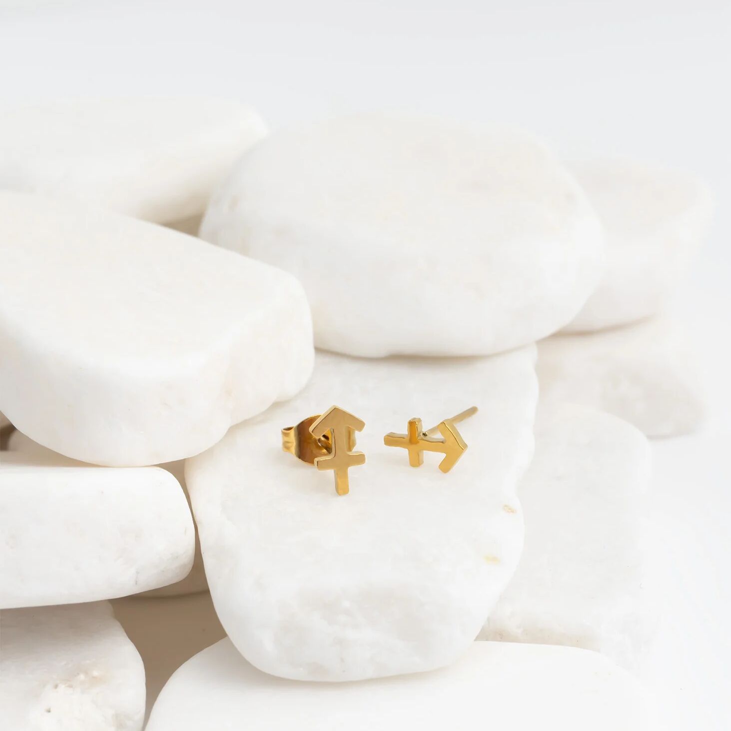 Gold earrings on a white stone surface