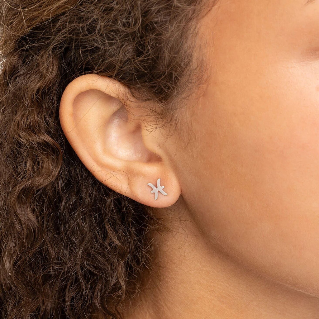 Close-up of an ear wearing an earring with dark hair in the background.