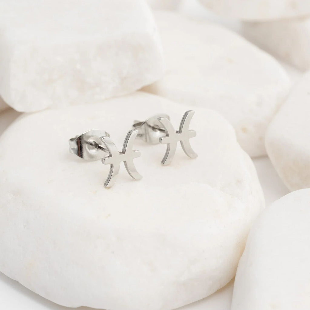 Zodiac Gemini earrings on a white stone background