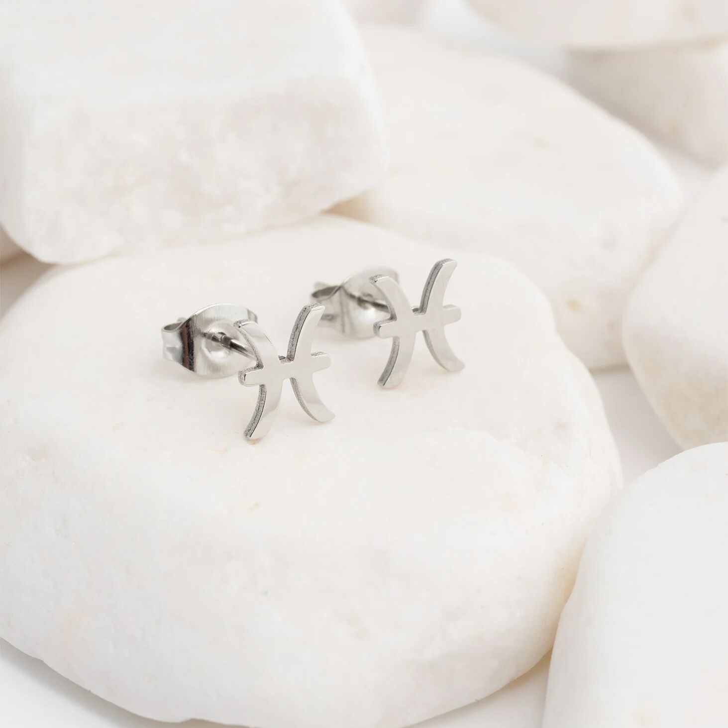 Zodiac Gemini earrings on a white stone background