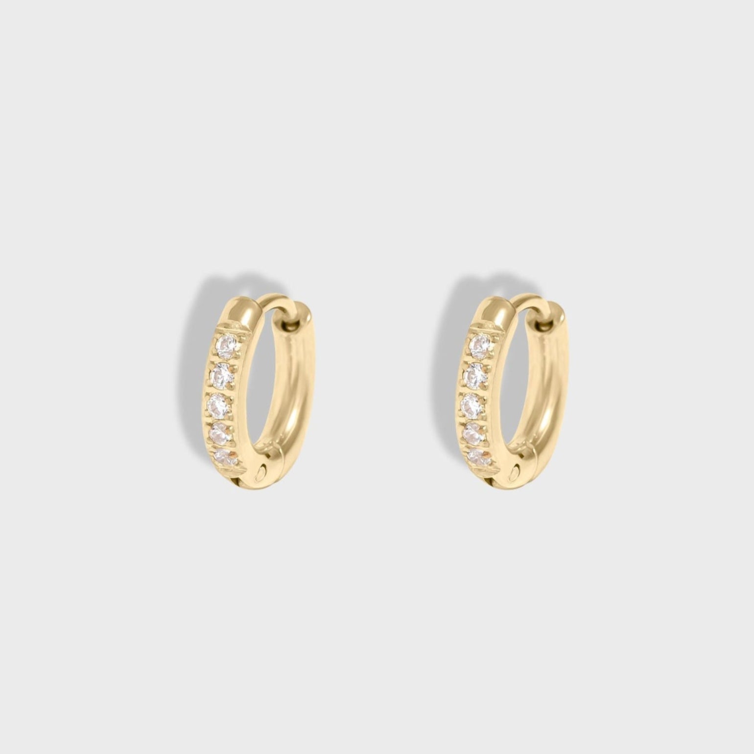Gold hoop earrings with embedded stones on a light gray background