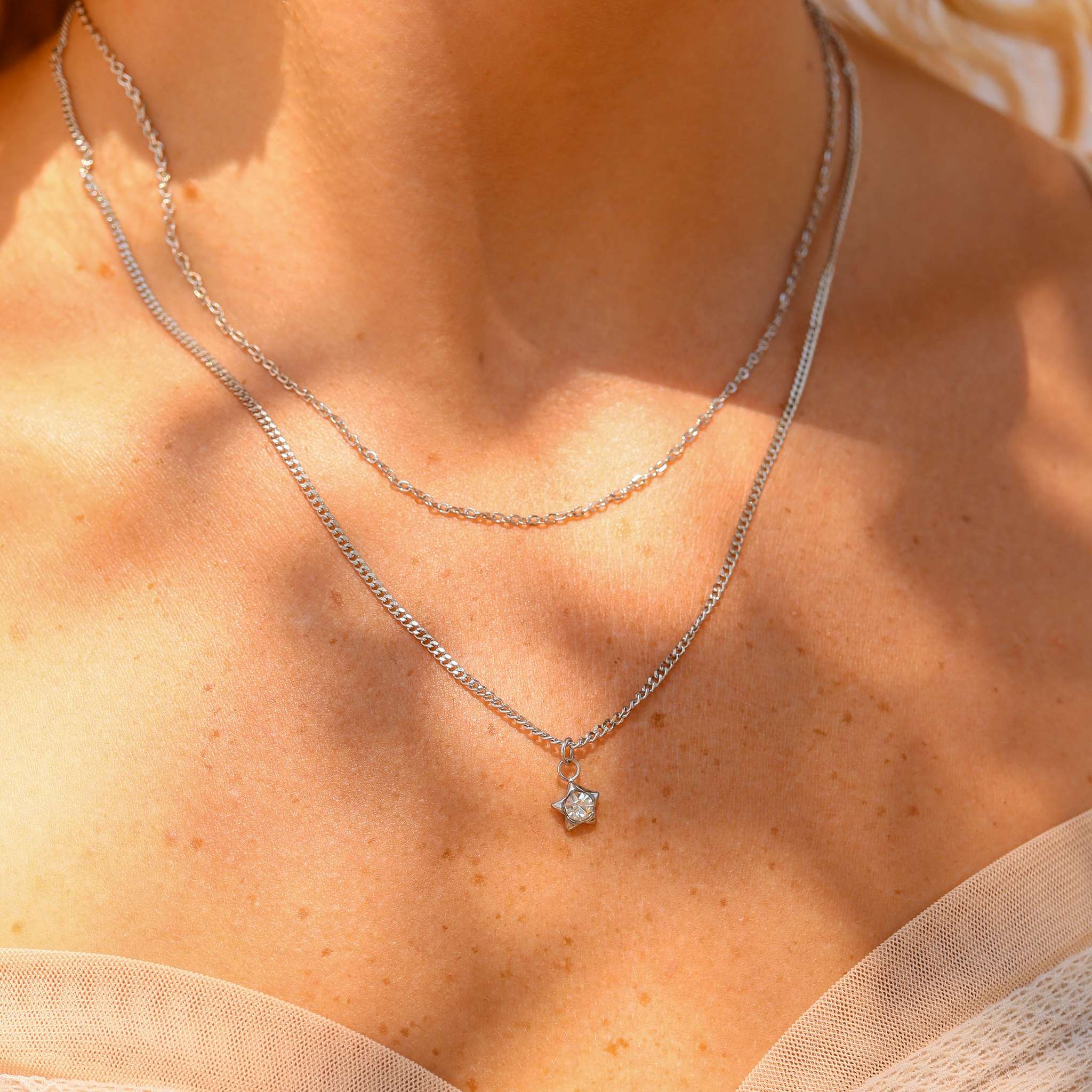 Silver necklace with a star pendant on a person's neck