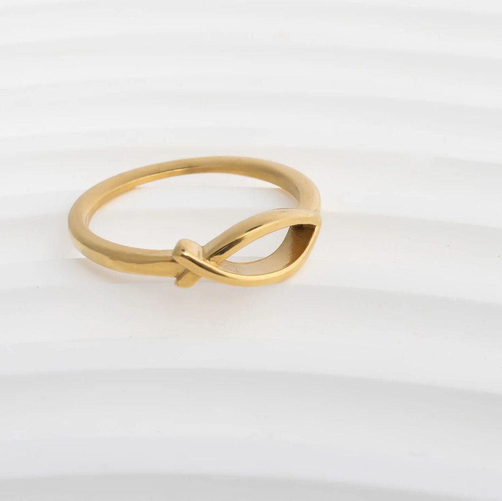 Gold ring with a knot design on a white background