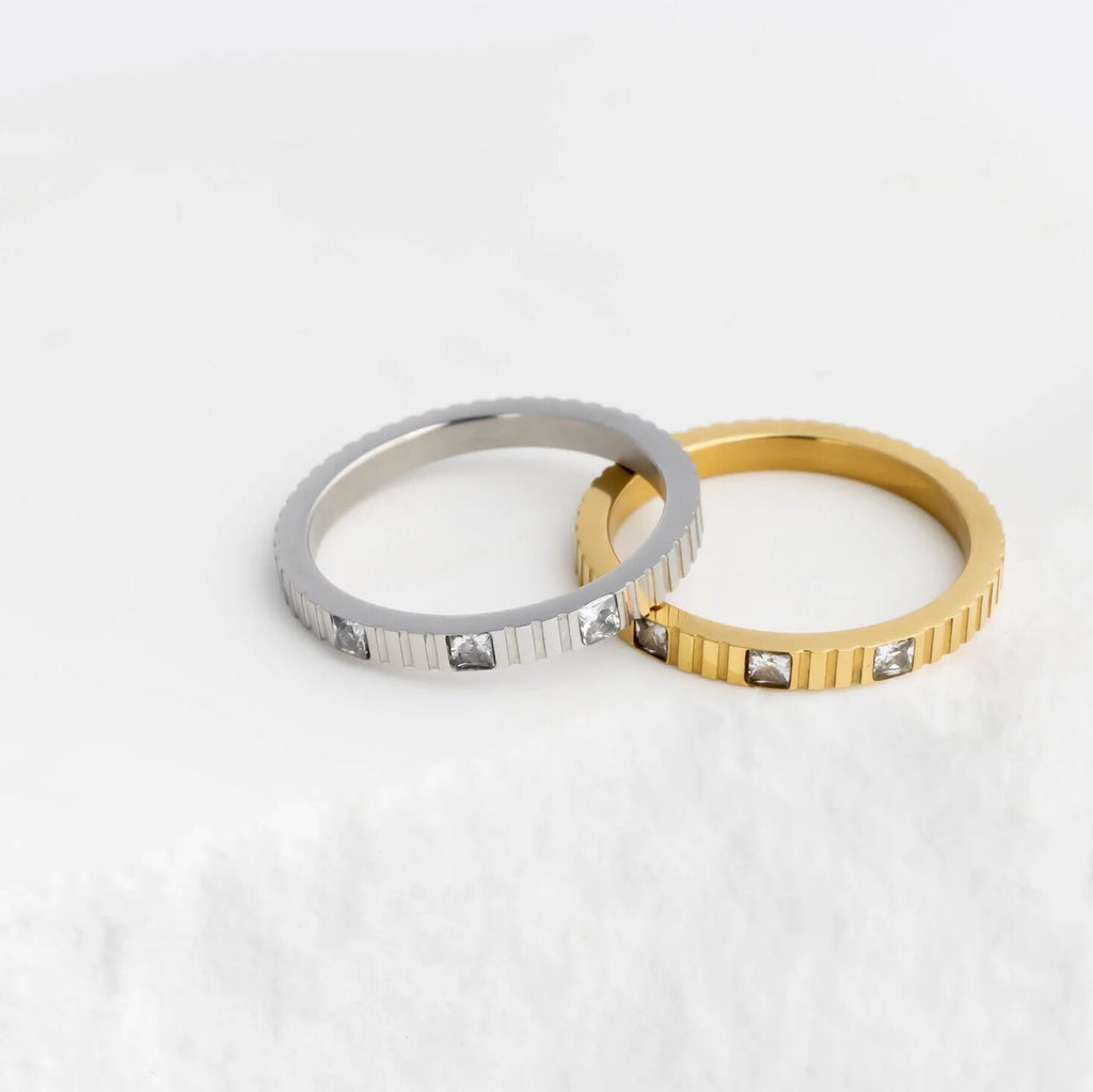 Two rings, one silver and one gold, with embedded stones on a white background