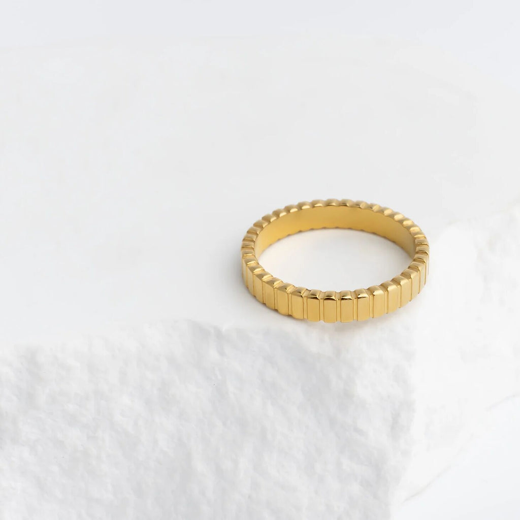 Gold ring with a textured band on a white background