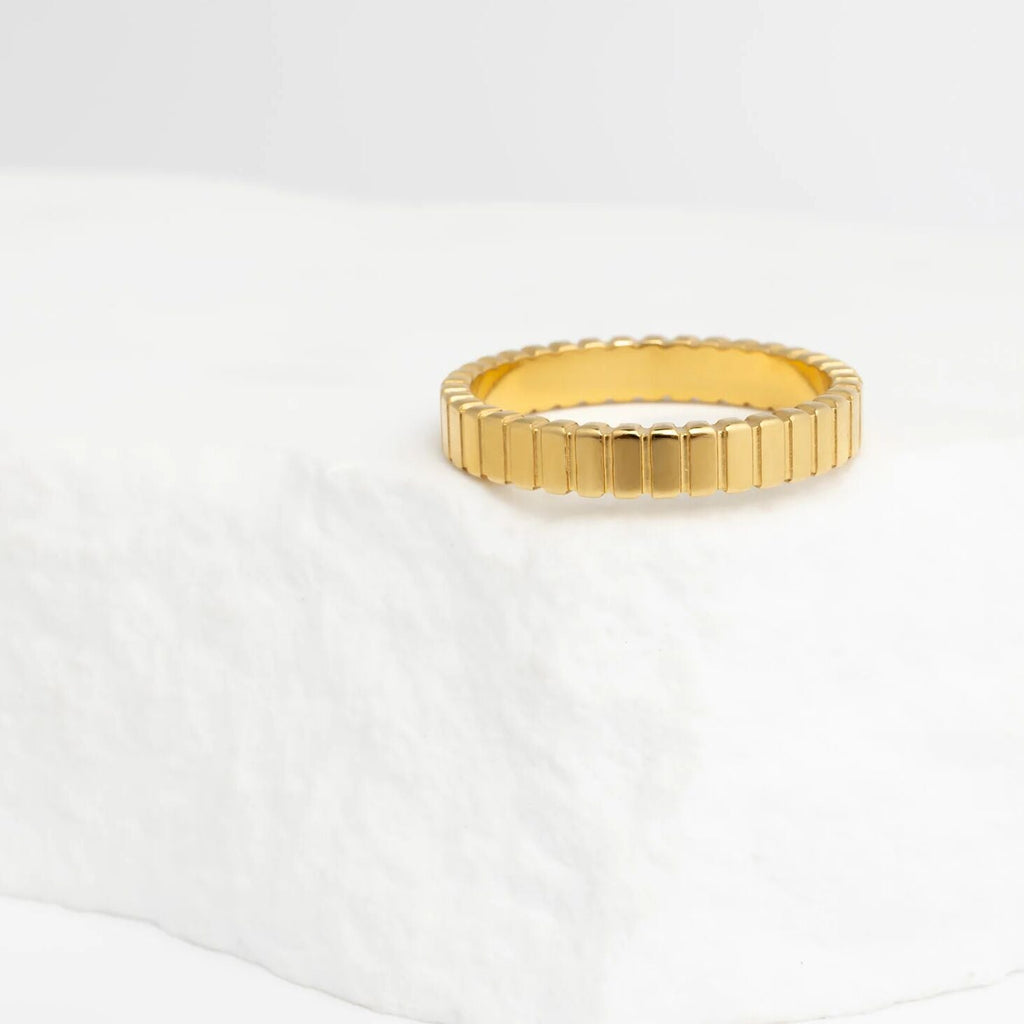 Gold ring with a textured band on a white background