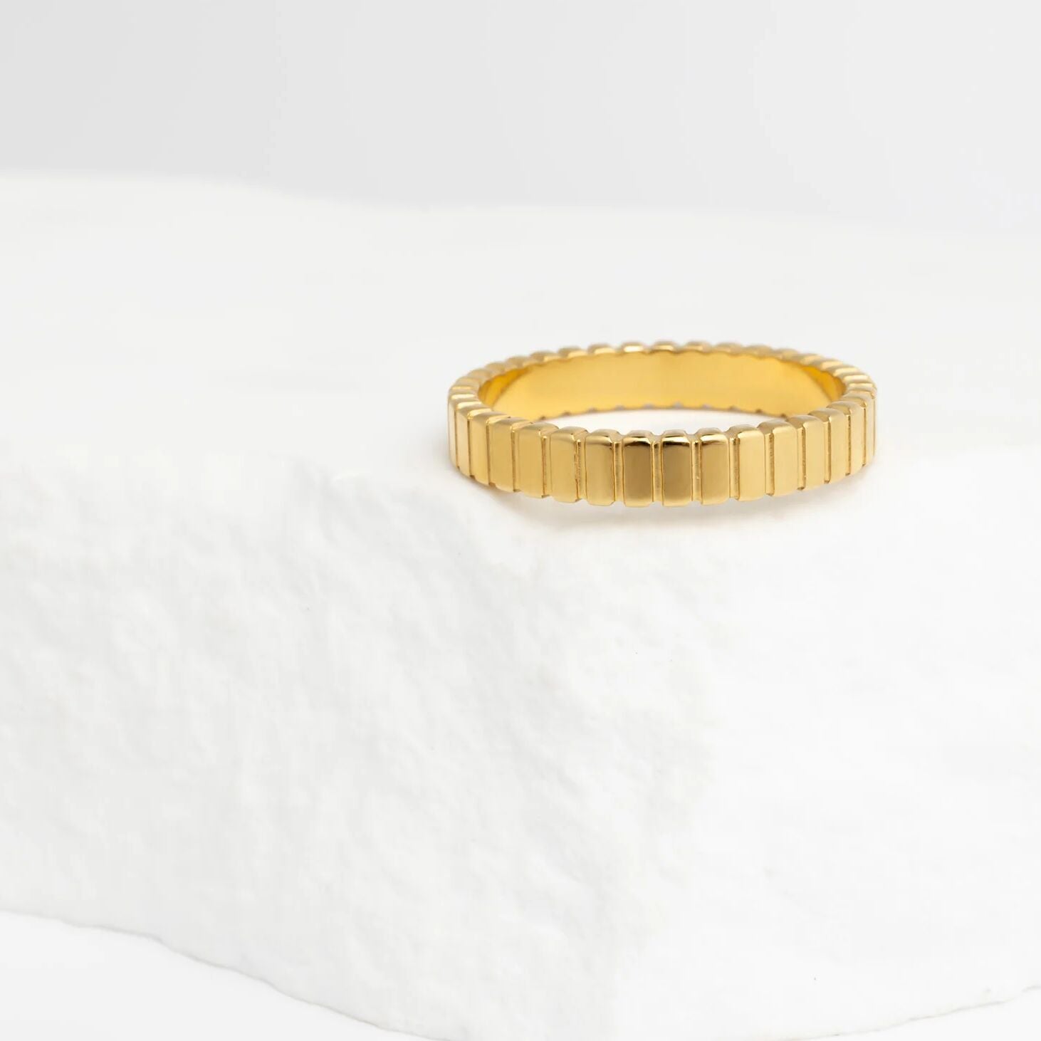 Gold ring with a textured band on a white background