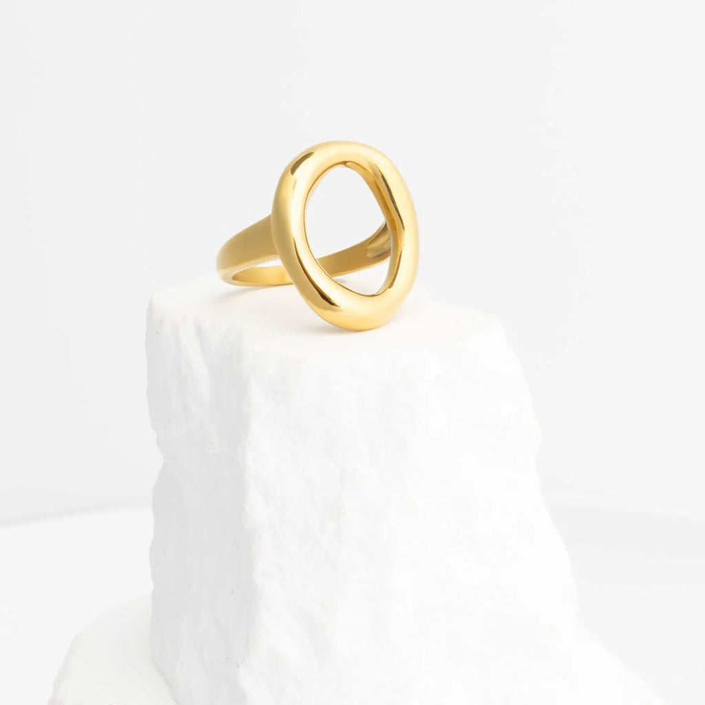 Gold oval ring on a white marble surface