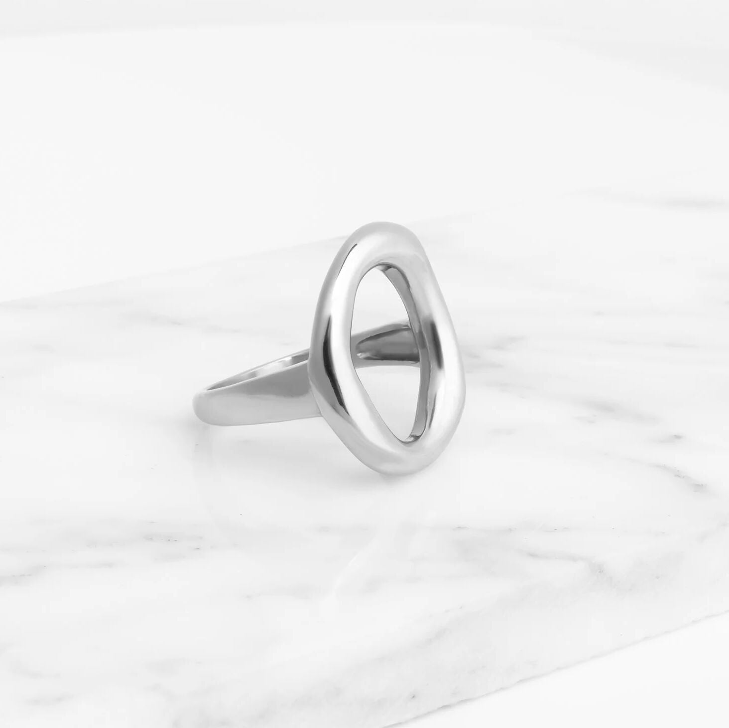Silver oval motif ring on a white marble surface
