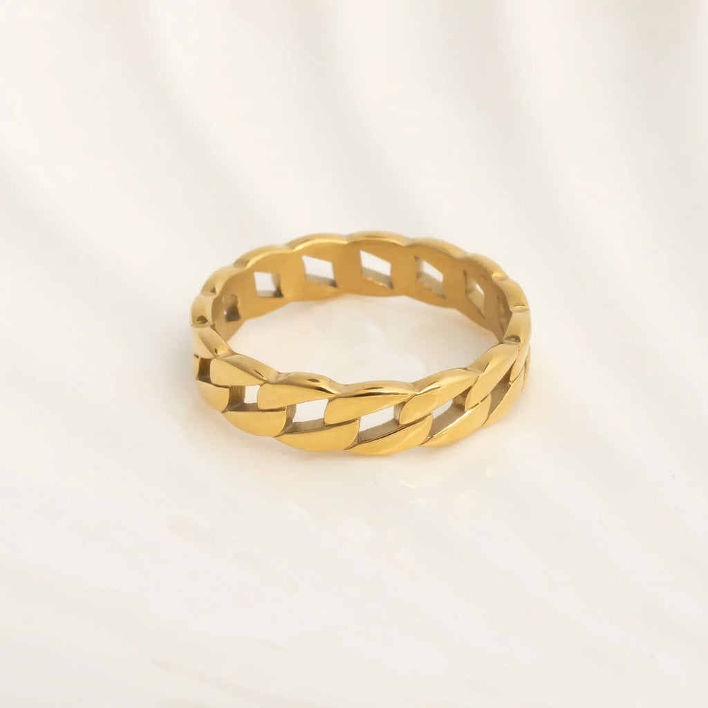 Gold ring with braided design on a light beige background