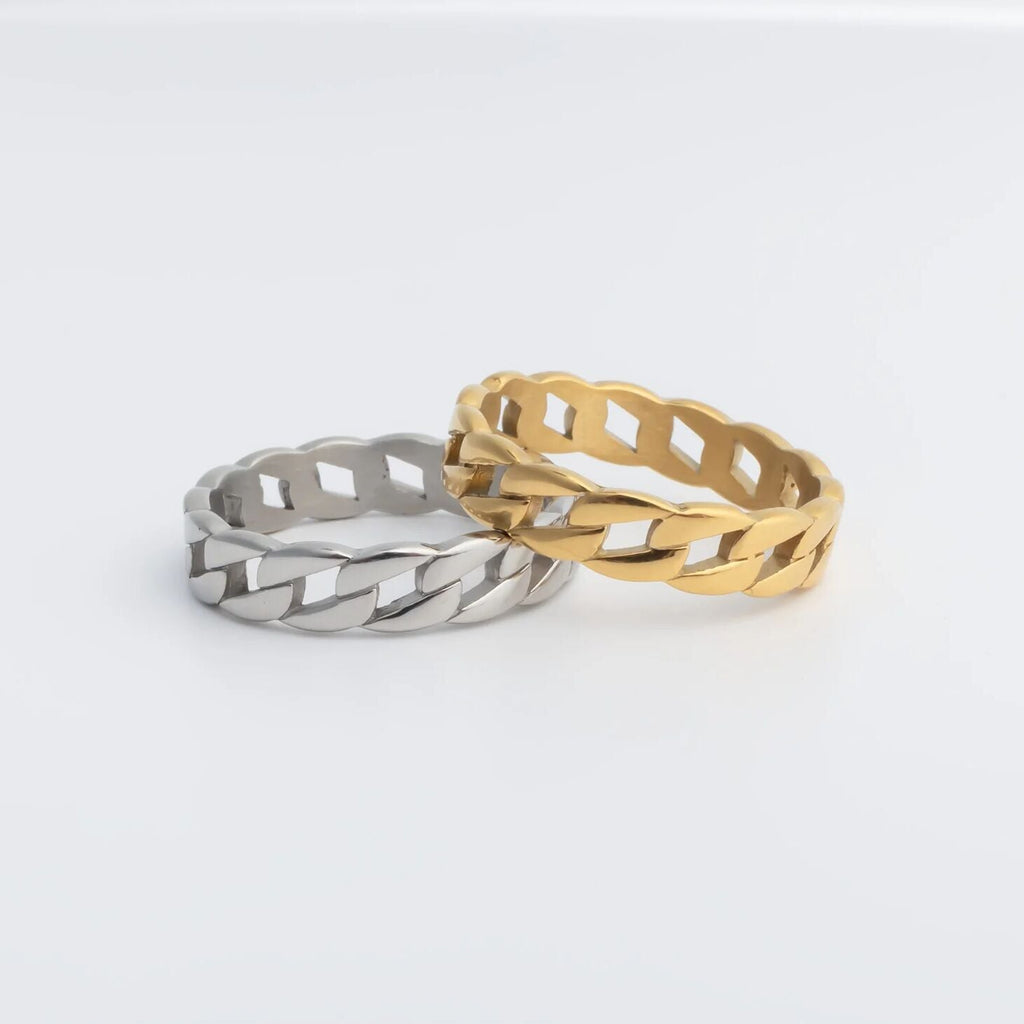 Two rings, one silver and one gold, on a light gray background