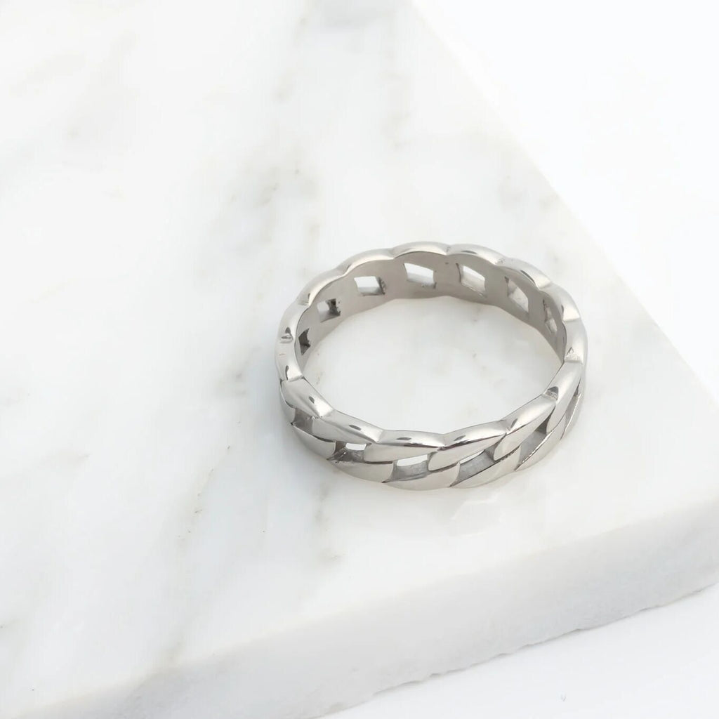 Silver ring with a textured band on a white marble surface