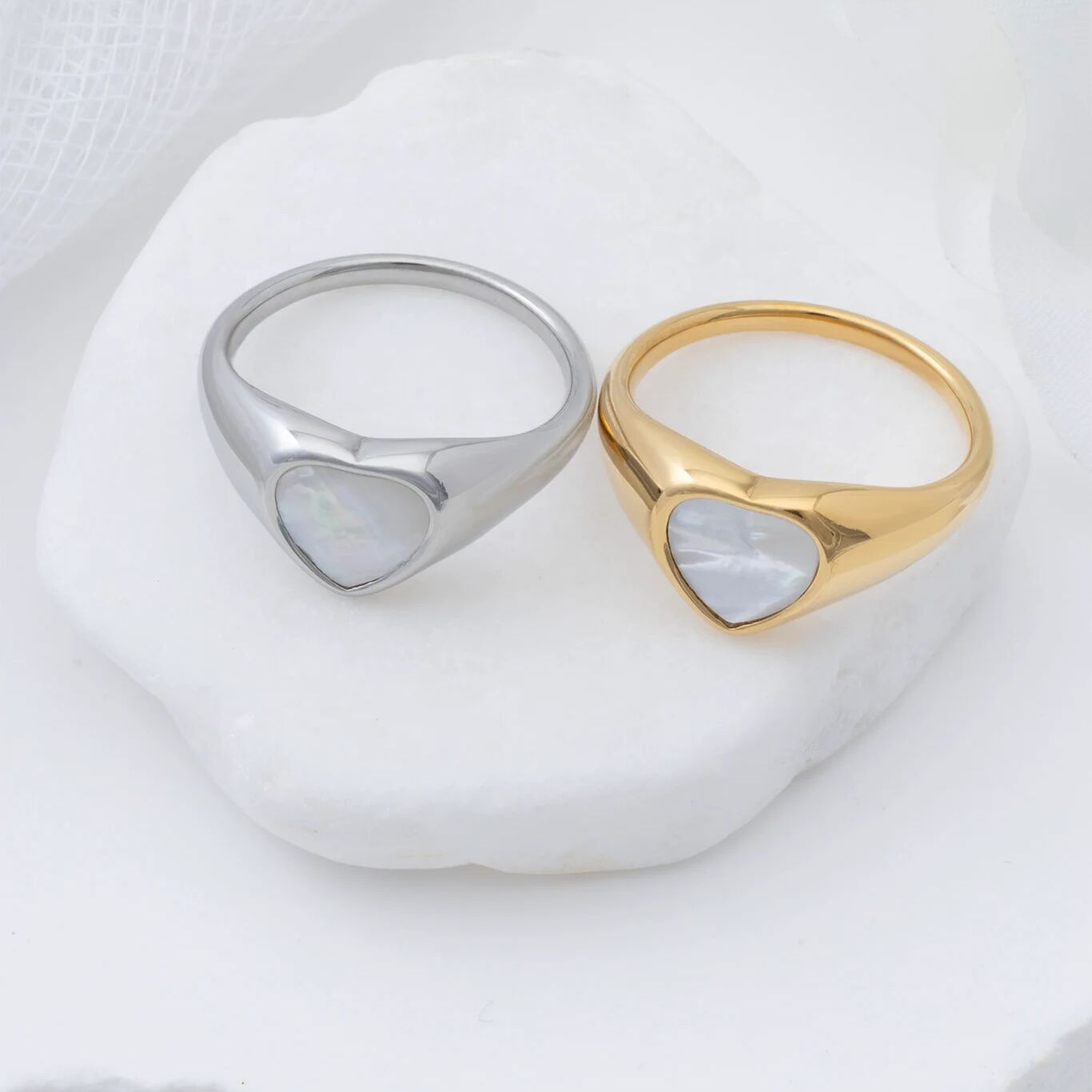 Two rings, one silver and one gold, on a white surface.