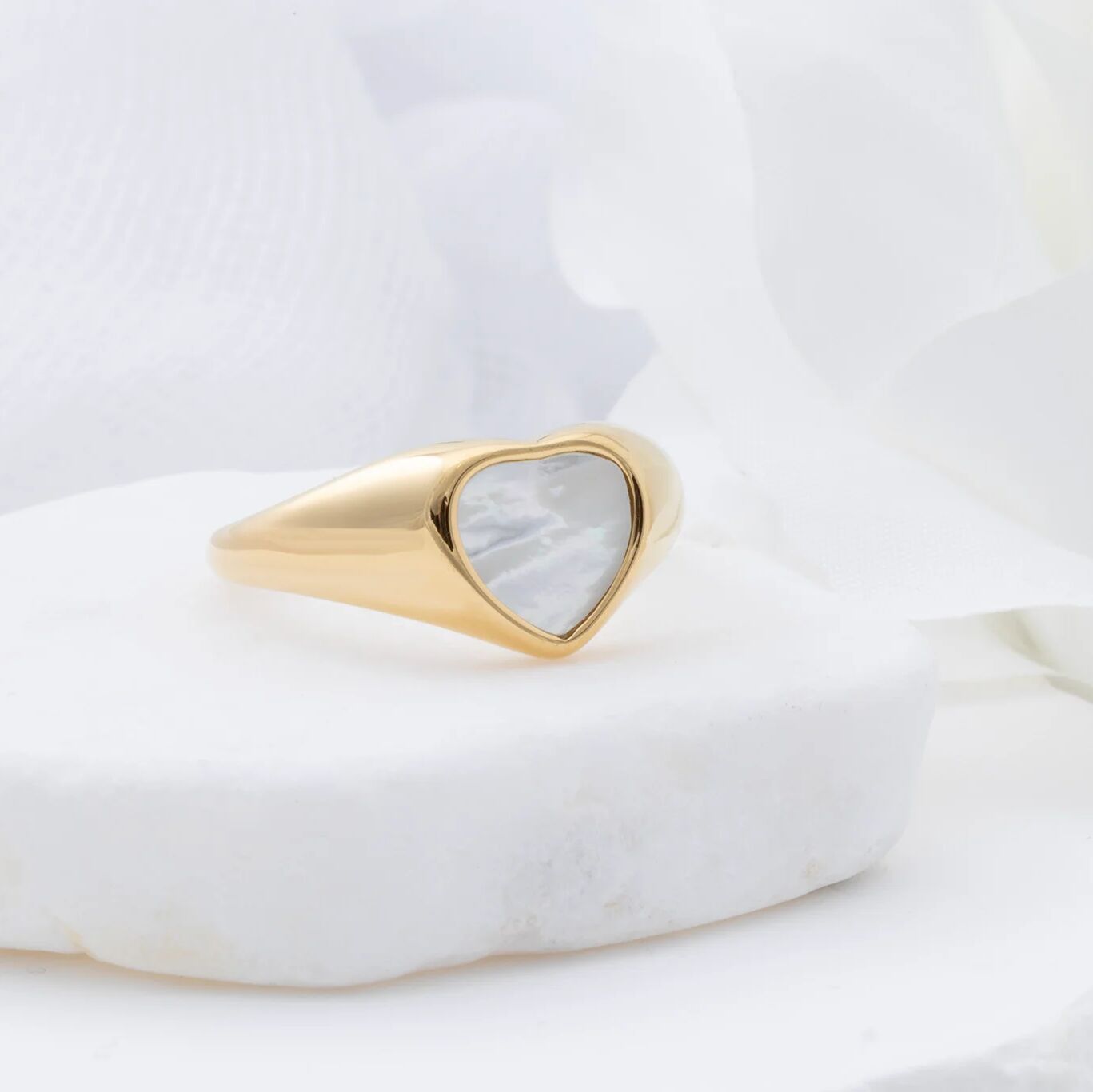 Gold MOP ring with a heart-shaped pearl on a white marble surface