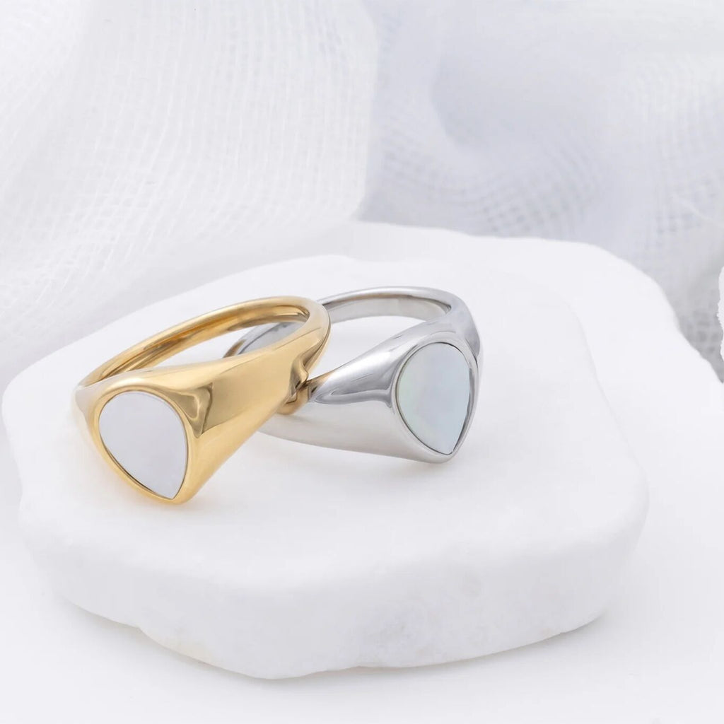 Two gold and silver rings on a white stone surface