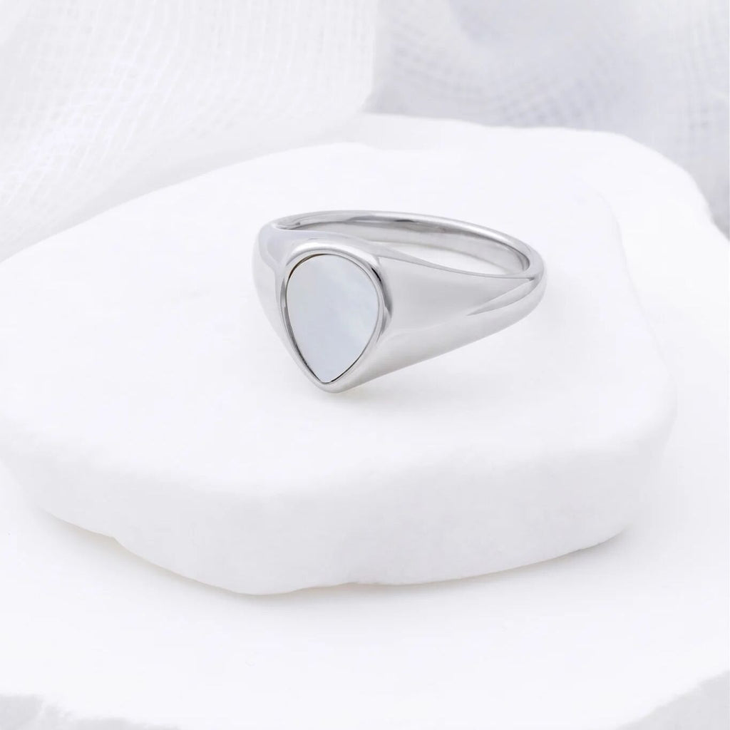 Silver signet ring on a white stone with a white background