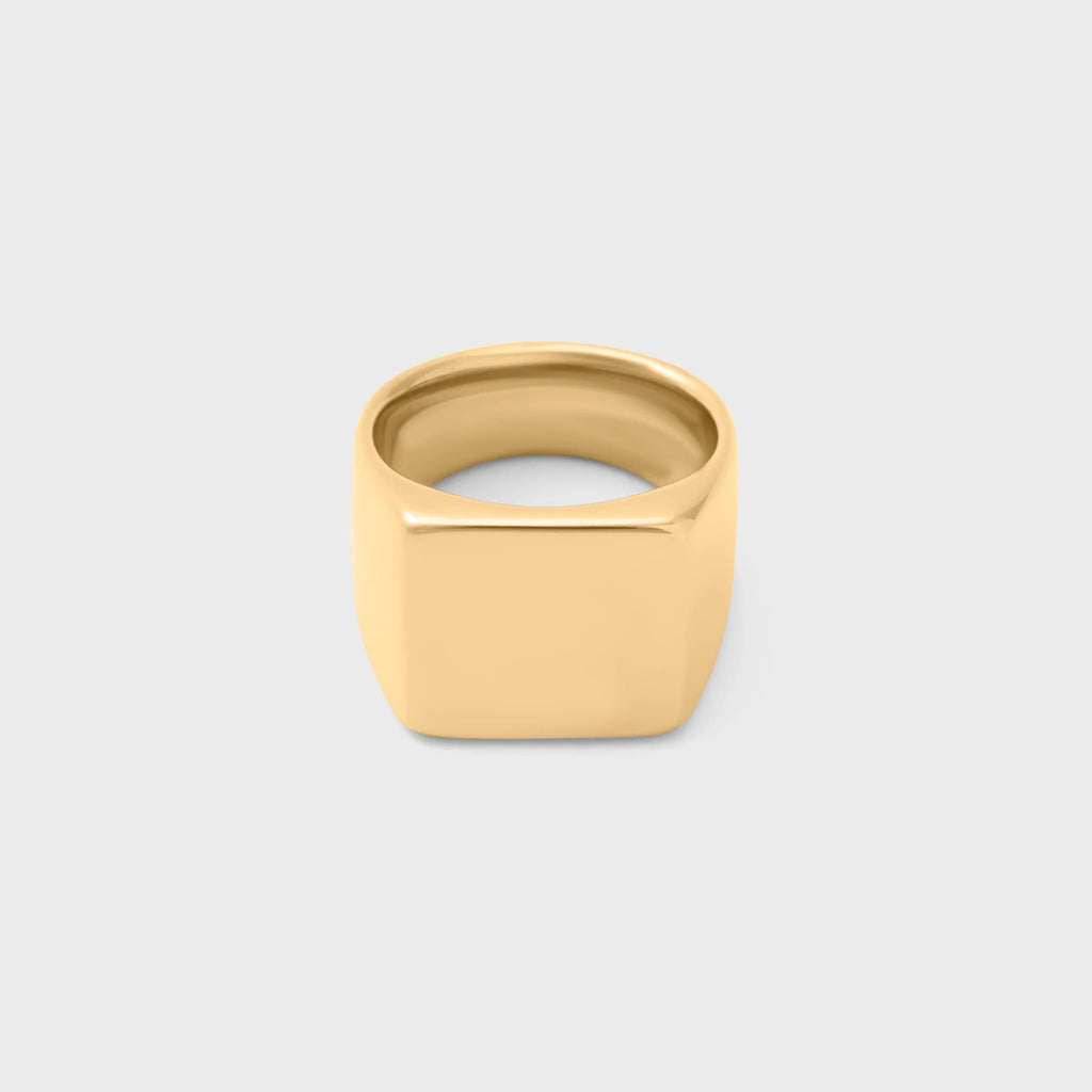 Gold square signet ring on a light gray background