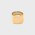 Gold square signet ring on a light gray background