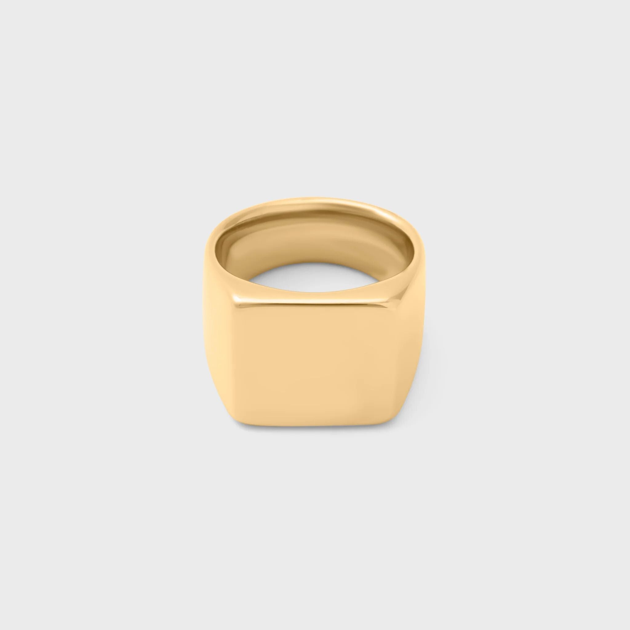 Gold square signet ring on a light gray background