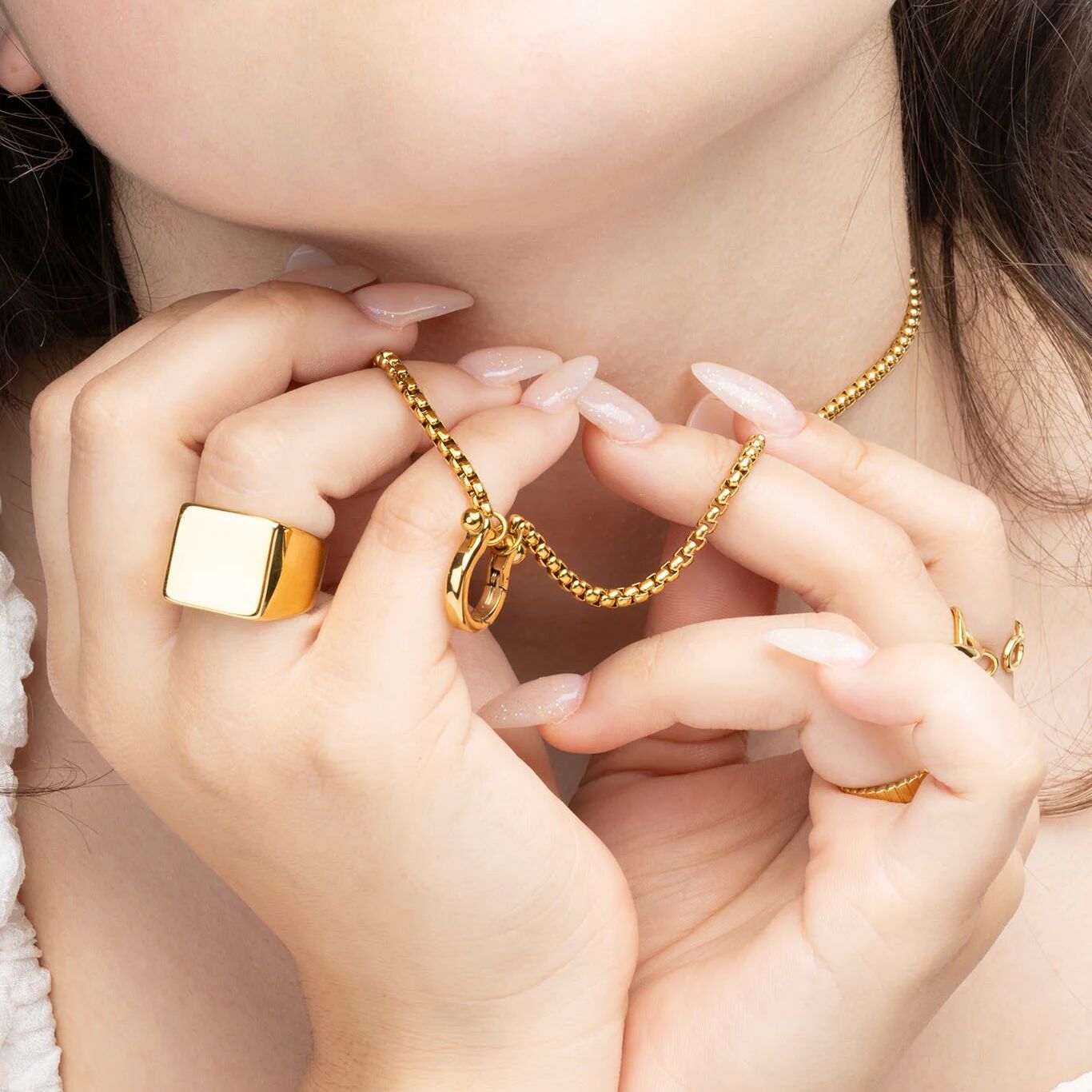 Close-up of hands wearing gold jewelry with a soft focus background