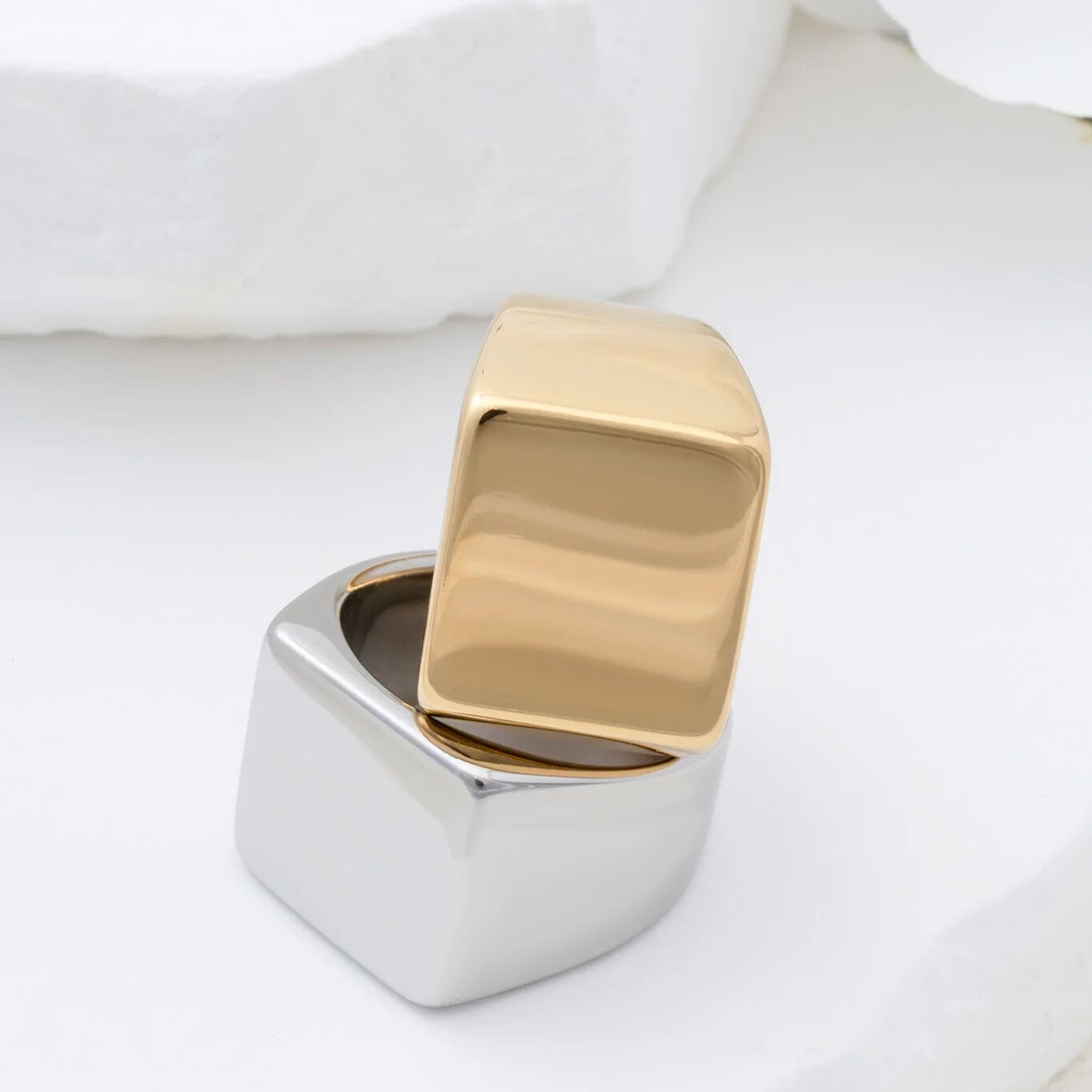 Gold and silver square signet ring on a white background