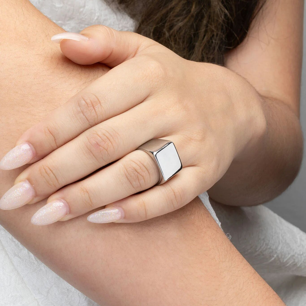 Close-up of a hand wearing a silver ring on a neutral background