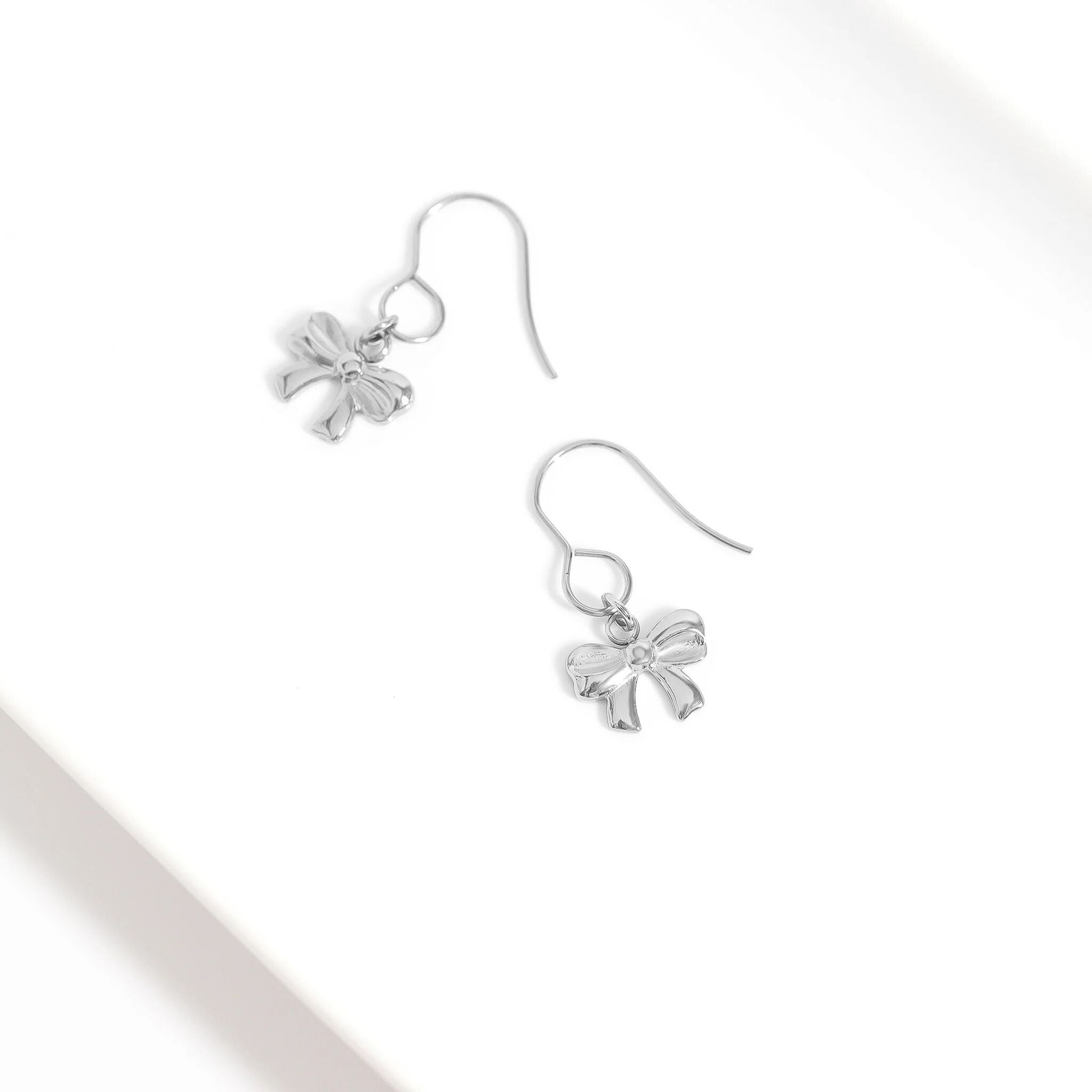Silver bow-shaped earrings on a white background