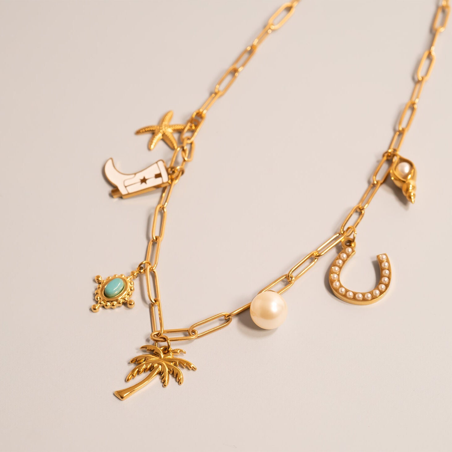 Gold chain necklace with various western charms including the Turquoise Compass Charm on a light gray background