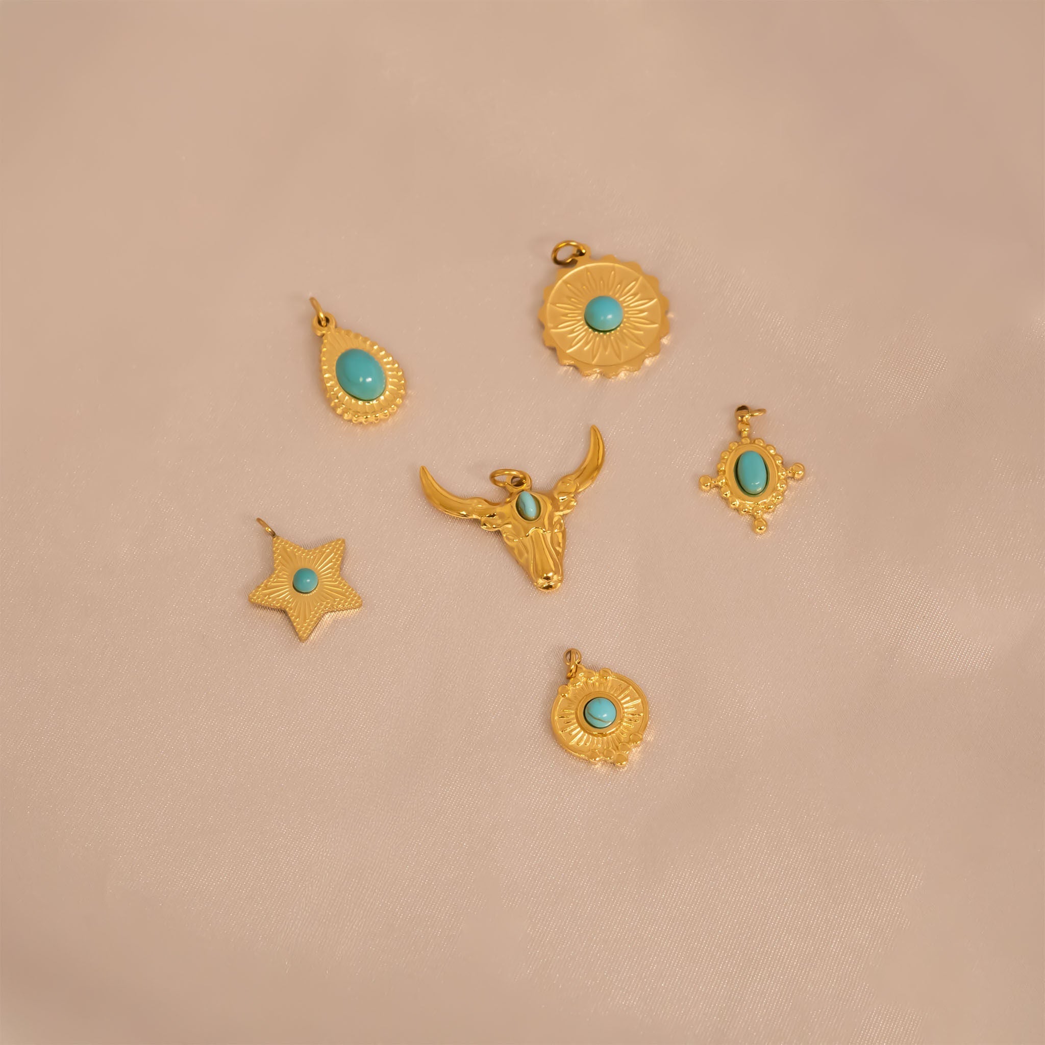 Set of western gold pendants with turquoise stones including the Turquoise Star Charm on a beige background