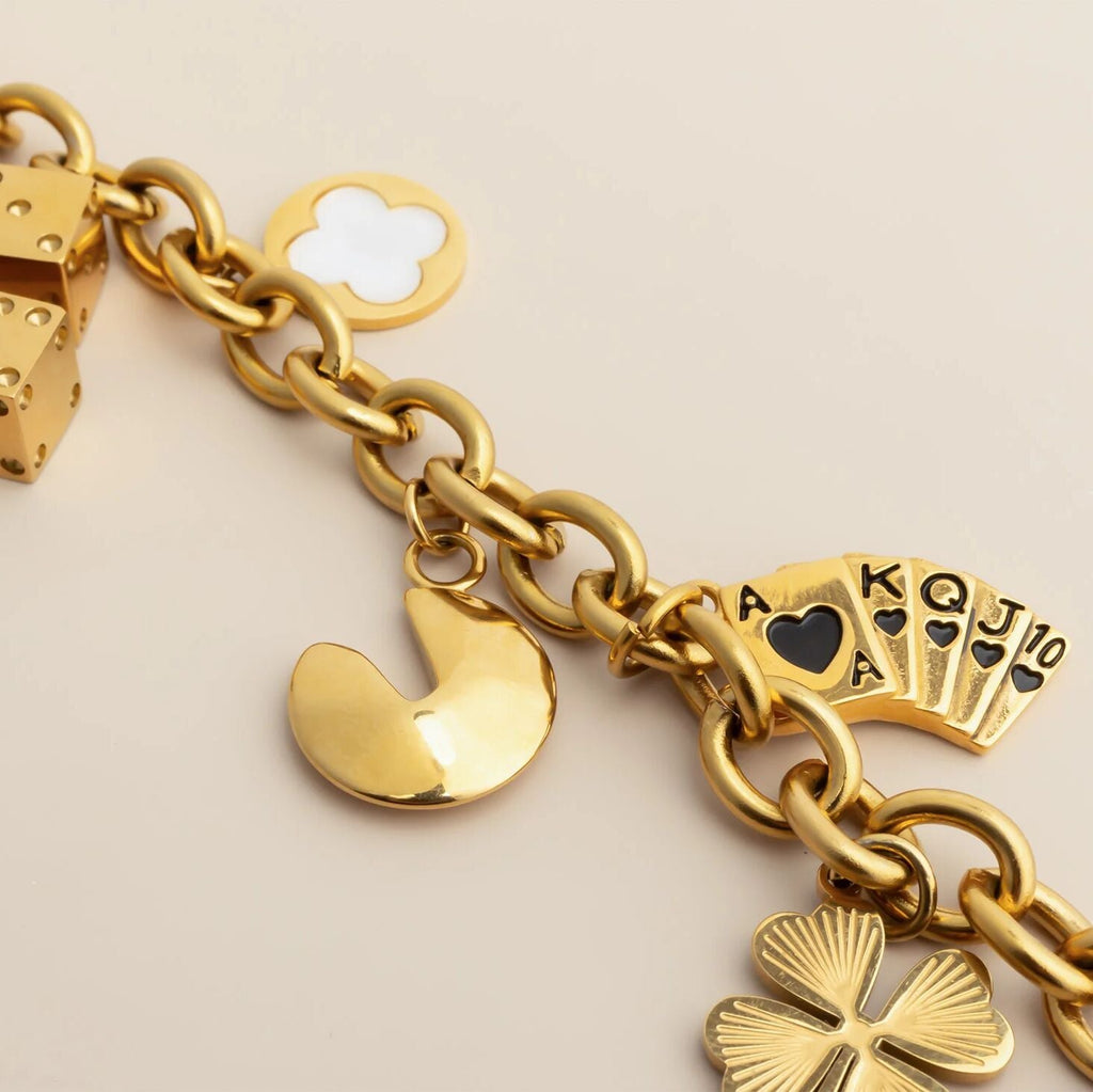 Gold charm bracelet with various charms on a beige background