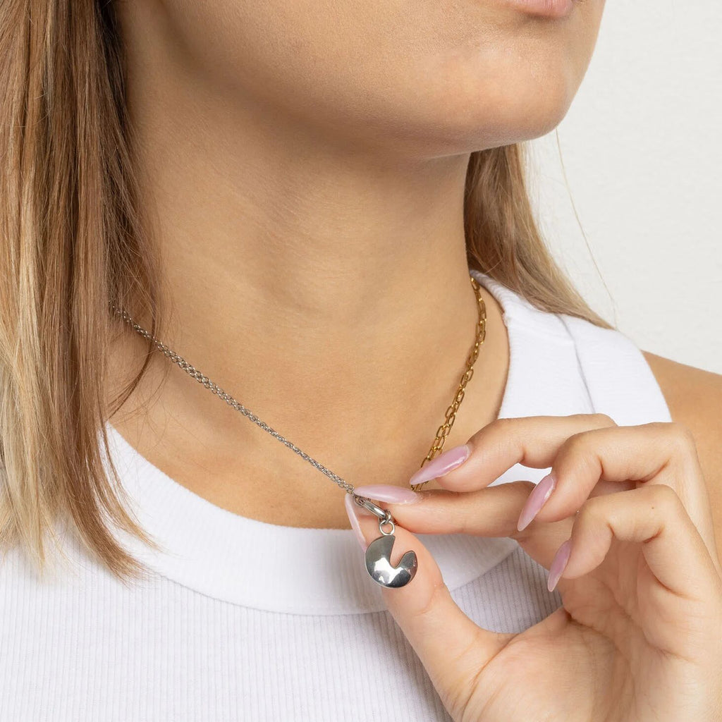 Close-up of a person wearing a necklace with a fortune cookie pendant.