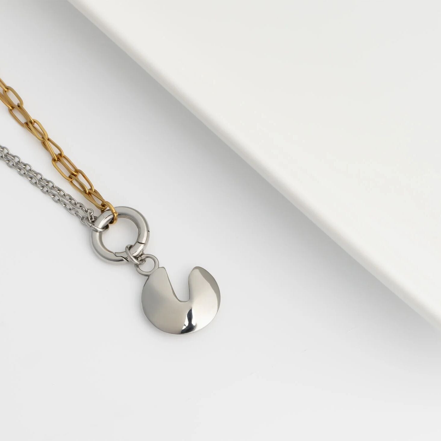 two toned necklace with a silver fortune cookie charm on a white background