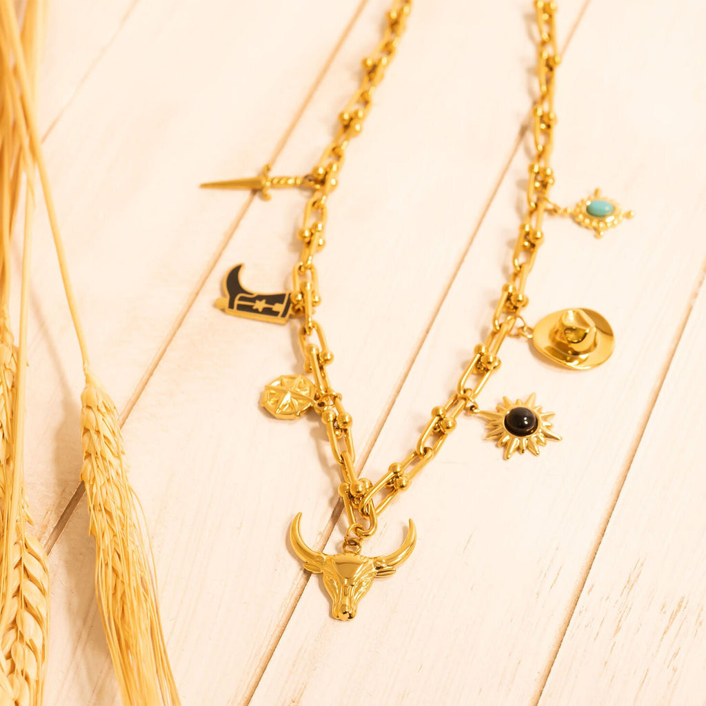 Gold necklaces with various western pendants on a light wooden surface