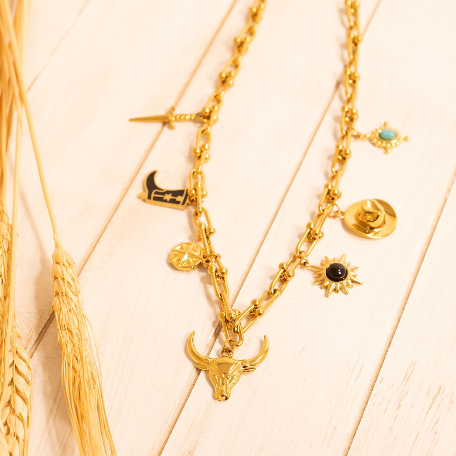 Gold necklaces with various western pendants on a light wooden surface