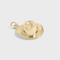 Gold cowboy hat and boot charm on a light gray background