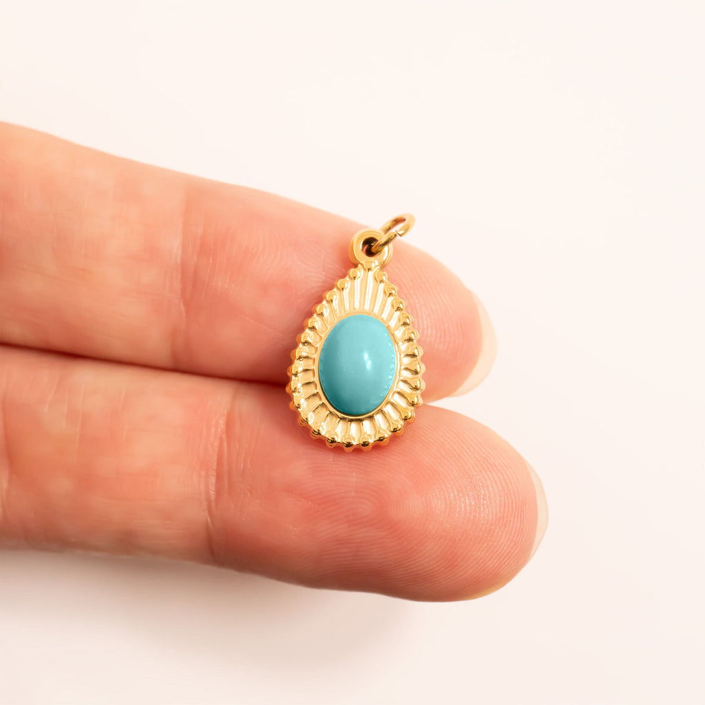 Turquoise Tear Drop Charm with a turquoise stone held between two fingers for scale on a white background
