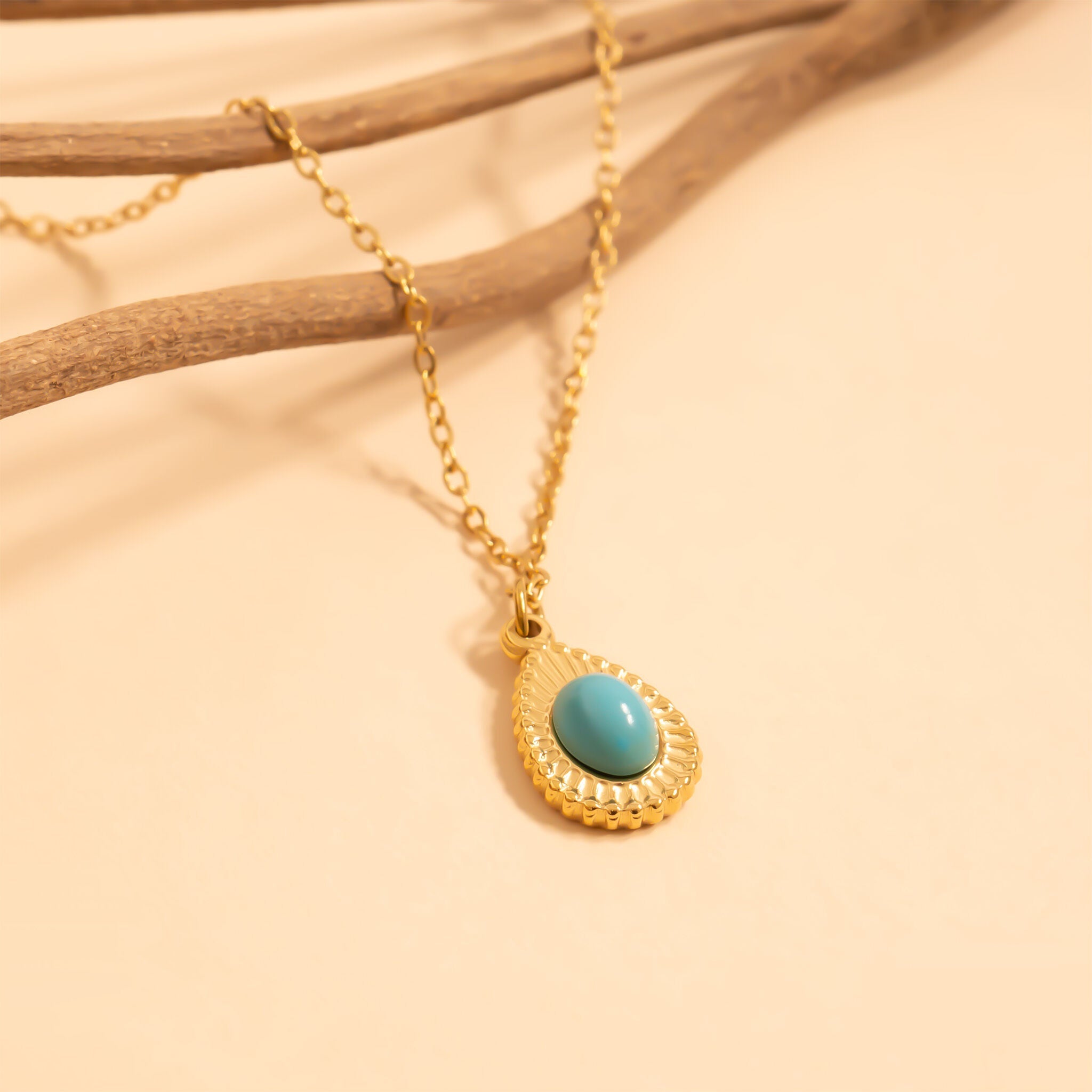 Gold necklace with a turquoise pendant on a beige background