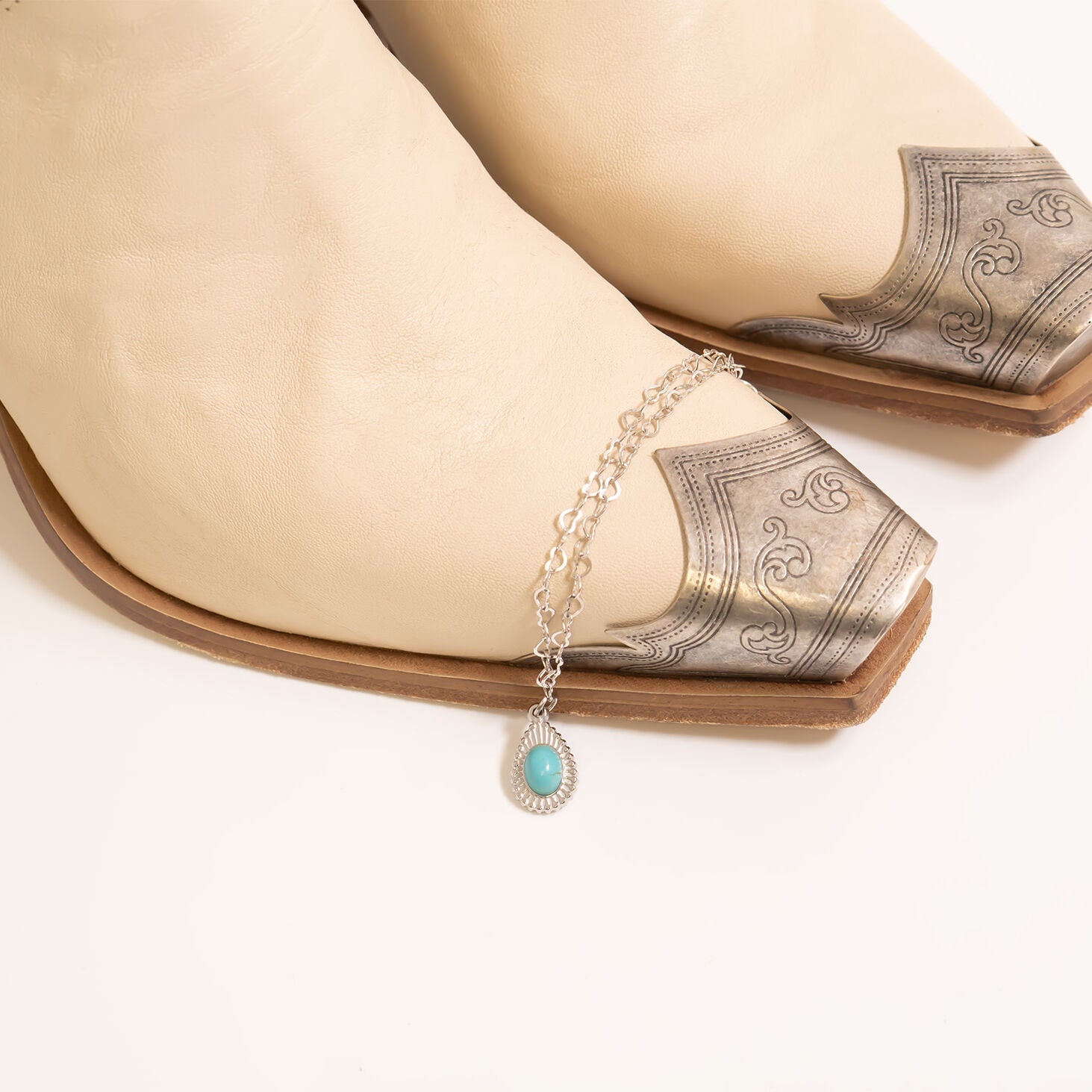 Turquoise pendant necklace on a beige cowboy boot with silver toe