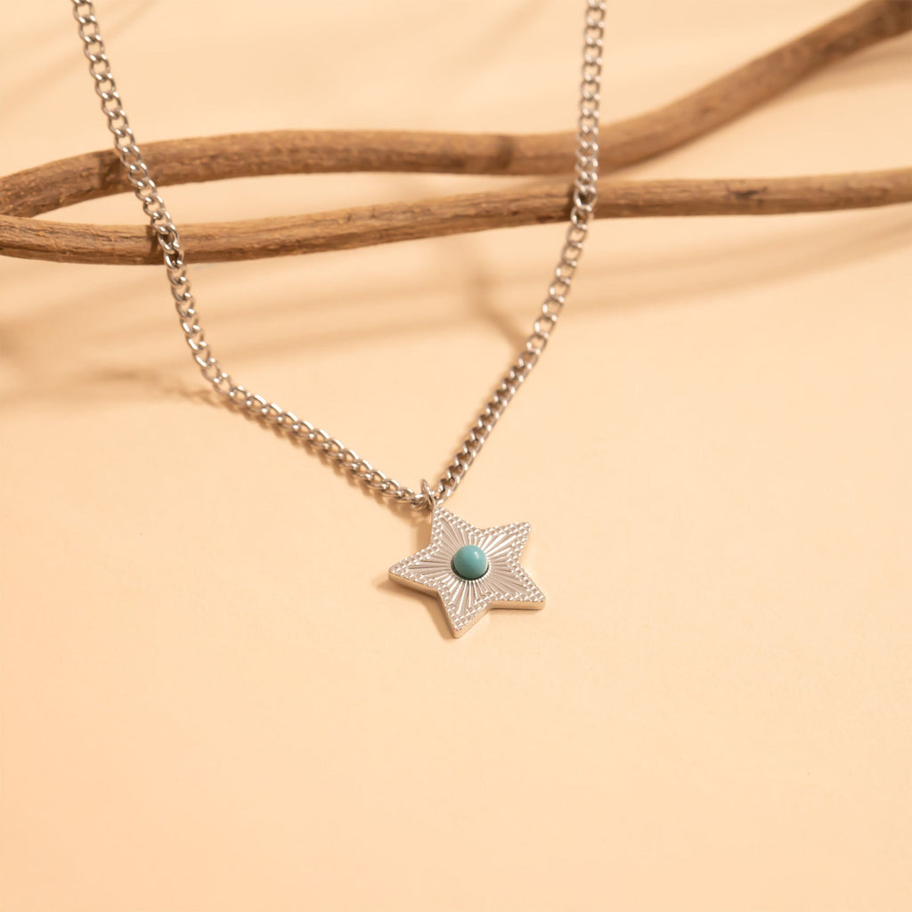 Star-shaped pendant necklace with a turquoise stone on a beige background