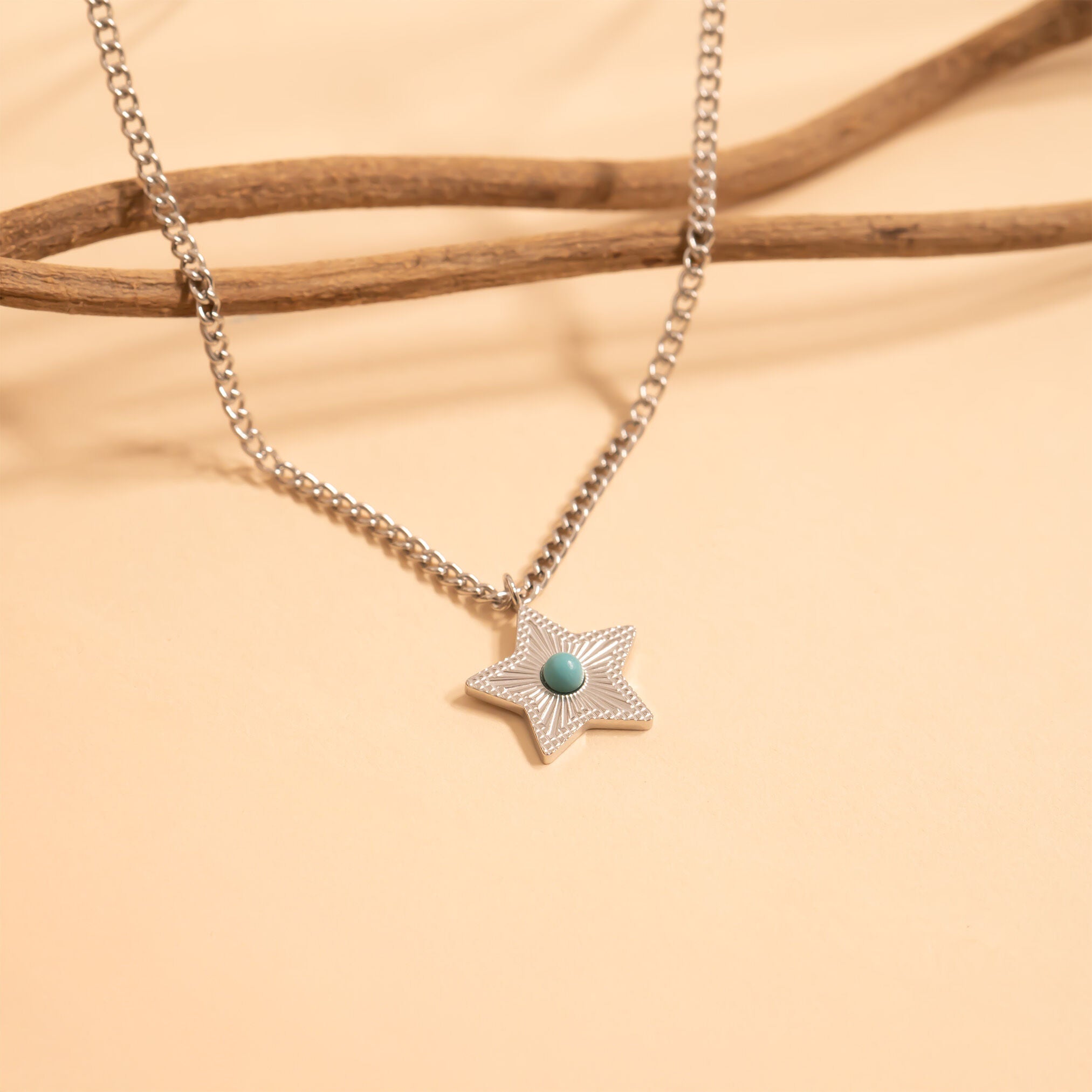 Star-shaped pendant necklace with a turquoise stone on a beige background